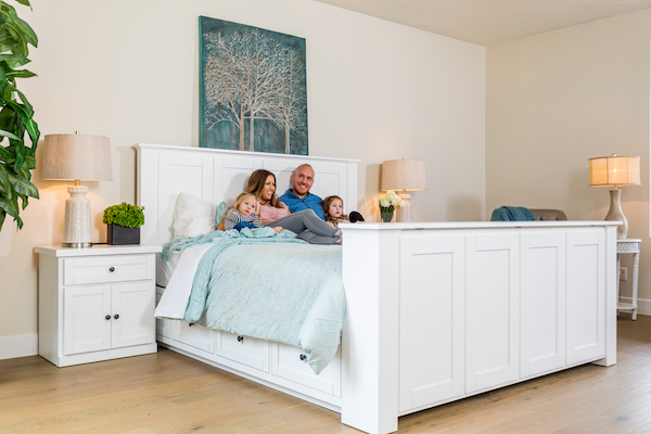 family sitting on a white tv bed